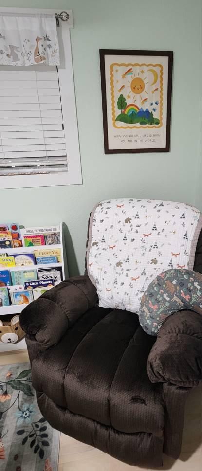 How Wonderful Life Is Now You're In The World print framed and hung above a brown recliner in a sage-green nursery reading corner
