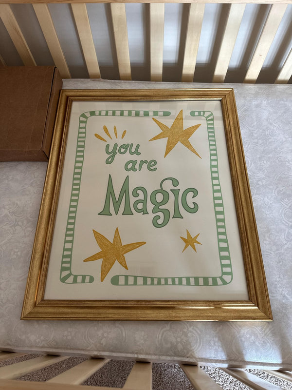 You Are Magic print in a gold frame resting on a crib in a nursery