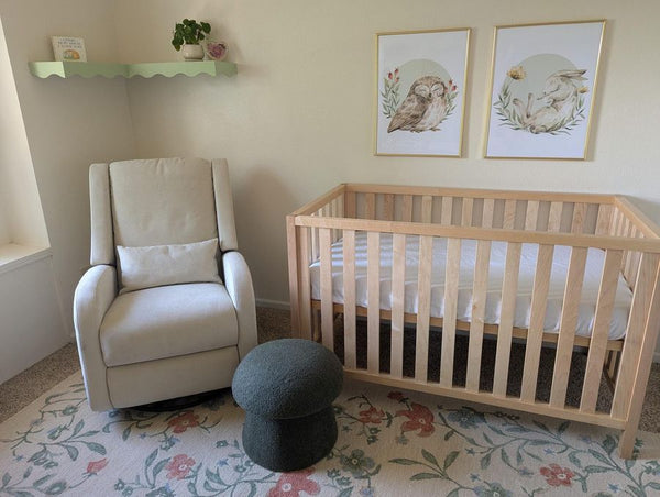 Framed owl and bunny woodland prints hanging above a nursery crib and glider chair