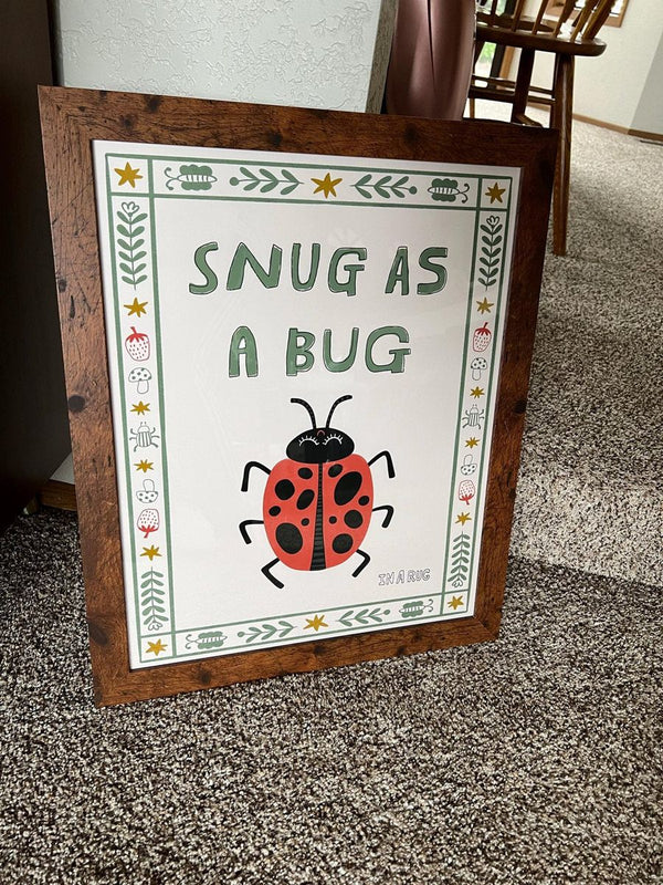 Snug As A Bug ladybug print in a rustic wood frame in a living room