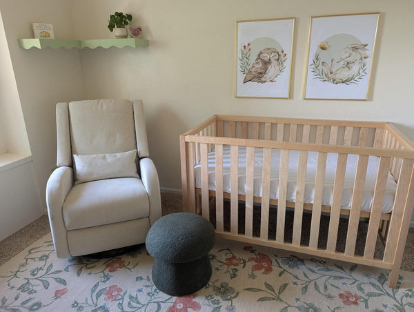 Framed owl and bunny woodland prints hanging above a nursery crib and glider chair