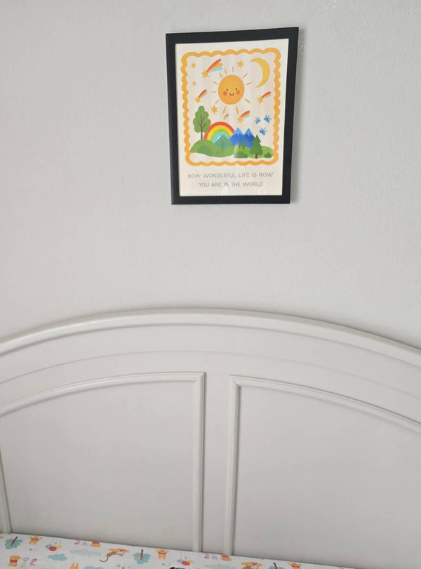 How Wonderful Life Is Now You're In The World print framed in black and hung above a white arched headboard bed
